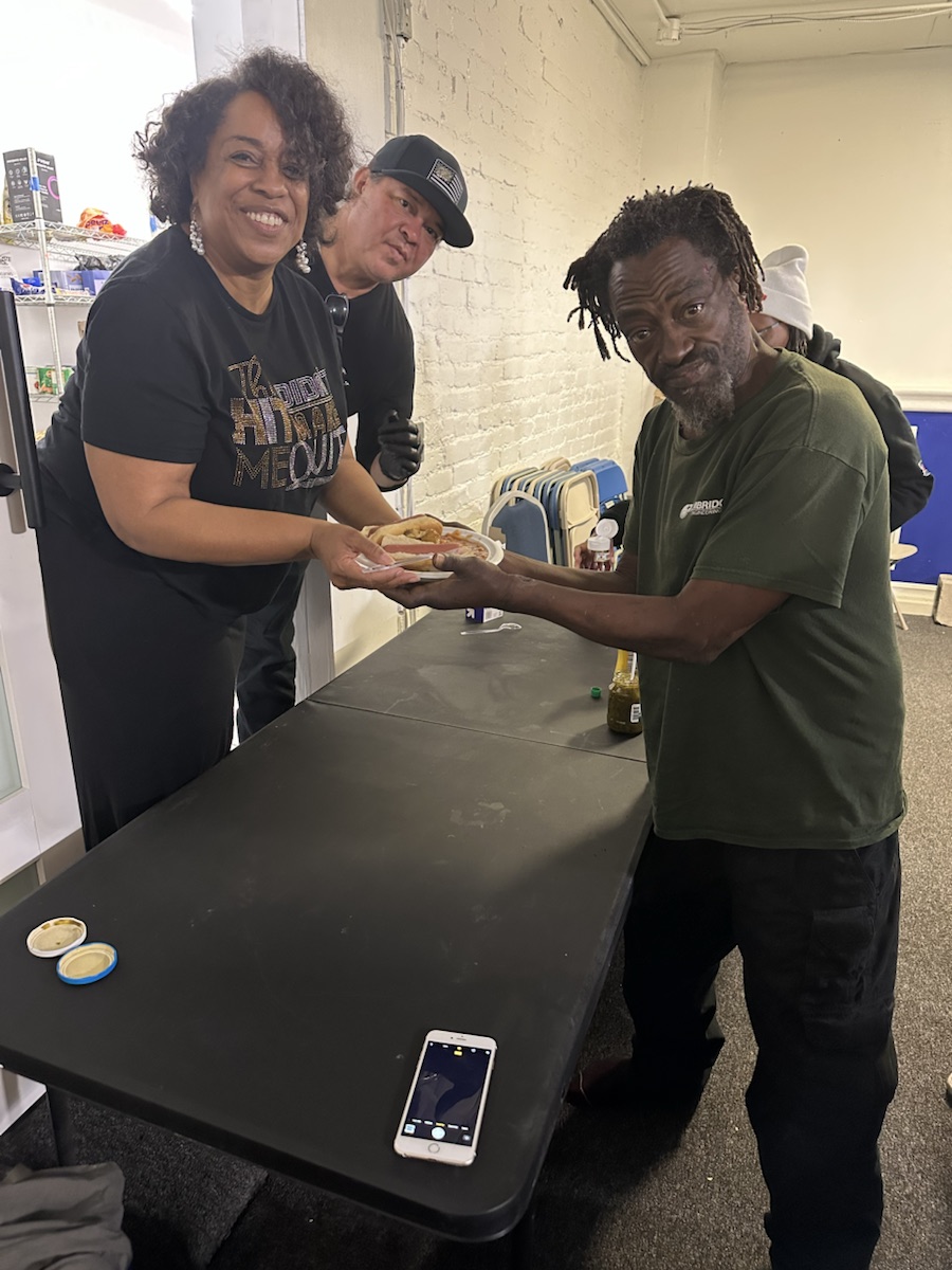 A God Loves House of Ministries volunteer serving a meal to a community member